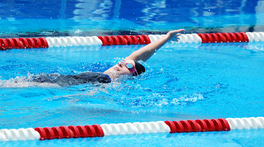 Frau beim Rückenschwimmen im Schwimmbecken – gelenkschonender Sport zur Stärkung der Rückenmuskulatur und Linderung von Beschwerden bei Bandscheibenvorfall