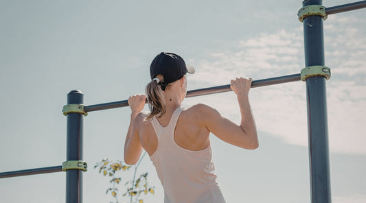 Sportlerin macht Klimmzüge im Outdoor-Fitnesspark