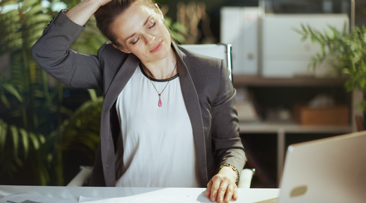 Frau dehnt Nacken gegen Verspannungen im Büro