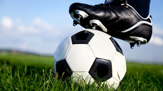 Fußballschuh auf Ball im Gras, Nahaufnahme Training oder Spielvorbereitung