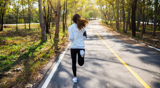 Joggerin läuft auf Waldstraße beim Ausdauertraining