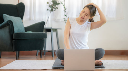 Frau macht eine Nacken-Dehnübung mit Online-Anleitung zu Hause