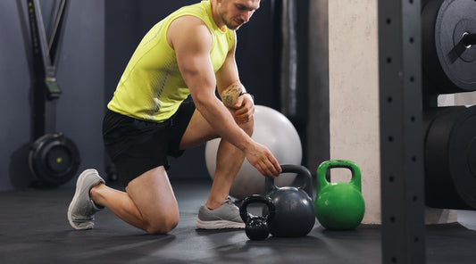 Mann beim Sport im Fitnesstudio mit Kugelhantel