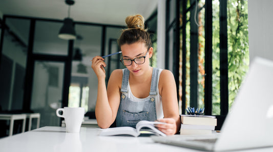 : Junge Frau lernt konzentriert mit Büchern im modernen Arbeitsraum