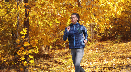 Frau joggt im Herbst durch den Wald