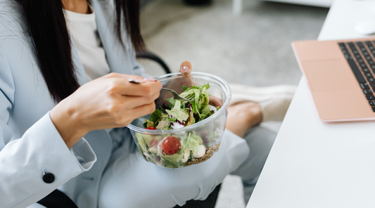Frau isst gesunden Salat während der Arbeit am Laptop