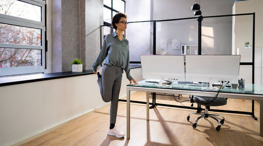 Frau dehnt sich im Büro neben dem Schreibtisch