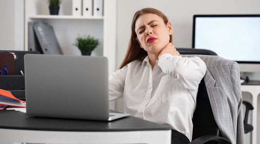 Büroangestellte mit schlechter Sitzhaltung leidet unter Nackenschmerzen am Arbeitsplatz