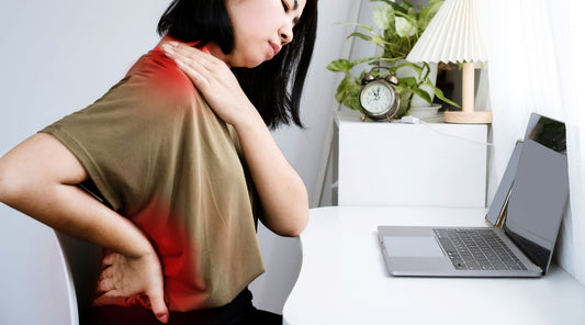 Frau mit Nacken- und Rückenschmerzen am Laptop