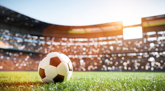 Fußball im Stadion bei Sonnenlicht, Spielszene mit Zuschauern im Hintergrund