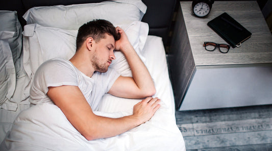 Mann schläft ruhig im Bett neben Nachttisch