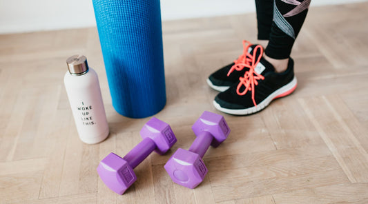 Fitness-Equipment mit Hanteln, Yogamatte und Sportschuhen