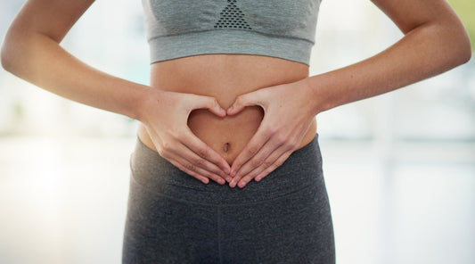 Frau formt Herz mit Händen über dem Bauch für Darmgesundheit