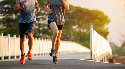 Paar joggt gemeinsam auf einer Brücke bei Sonnenaufgang am Morgen