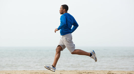 Mann joggt am Strand bei ruhigem Meer