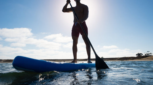 Mann beim Stand Up Paddling auf Wasser bei Sonnenschein
