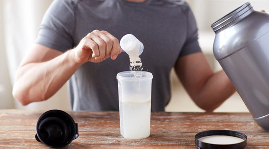 Mann füllt Proteinpulver in einen Shaker für Fitnessgetränk