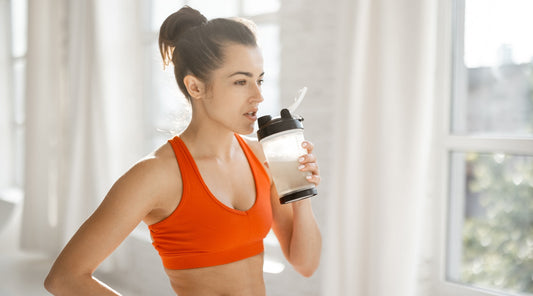 Sportlerin trinkt Proteinshake nach dem Training