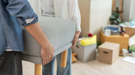 Zwei Personen tragen Sofa beim Umzug in Wohnung