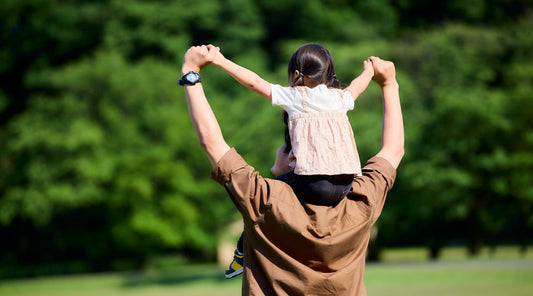 Vater trägt Kind auf den Schultern im Park