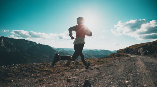 Trailrunner in den Bergen bei Sonnenaufgang auf Schotterweg