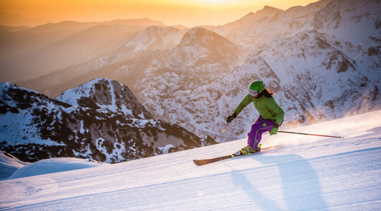 Skifahrerin bei Sonnenuntergang – Wintersport Tipps gegen Prellungen und blaue Flecken