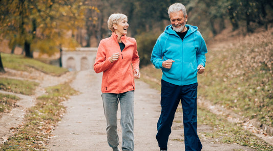 Älteres Paar joggt lachend durch einen herbstlichen Park Zone 2 Cardio